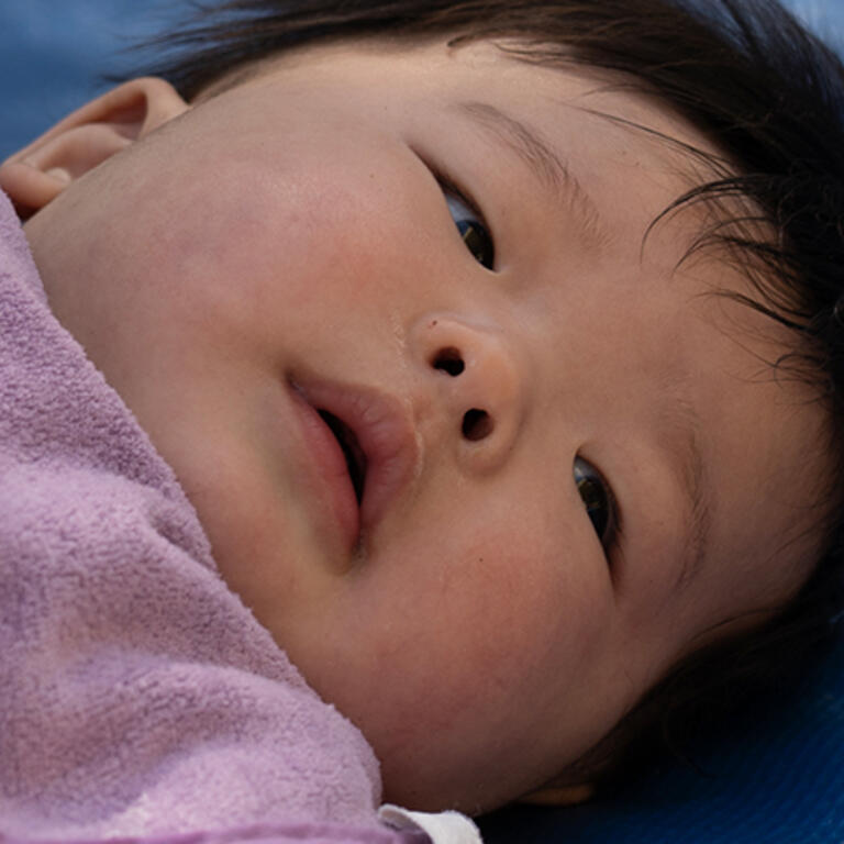 infant laying on mat on back