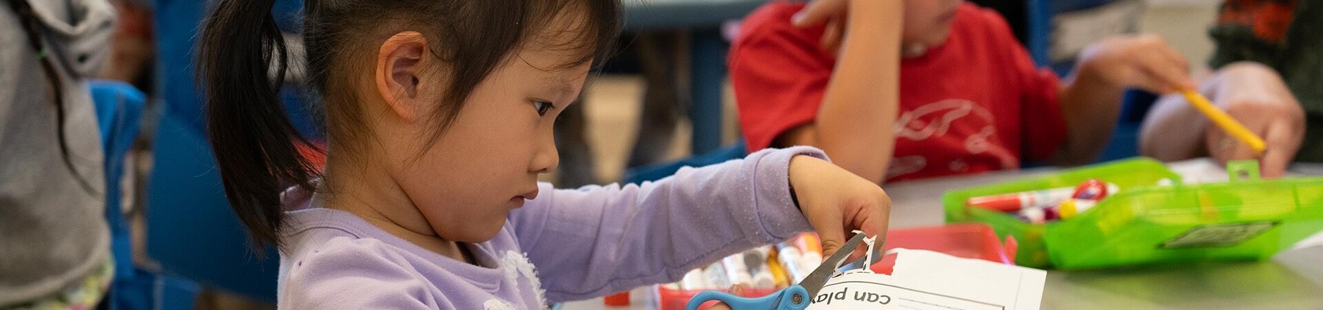A student cuts a piece of paper.