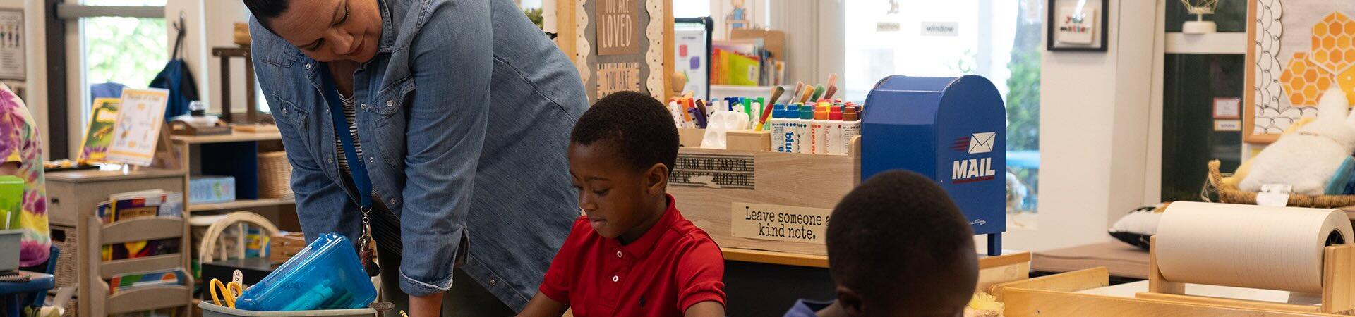 A kindergarten teacher helps a student.