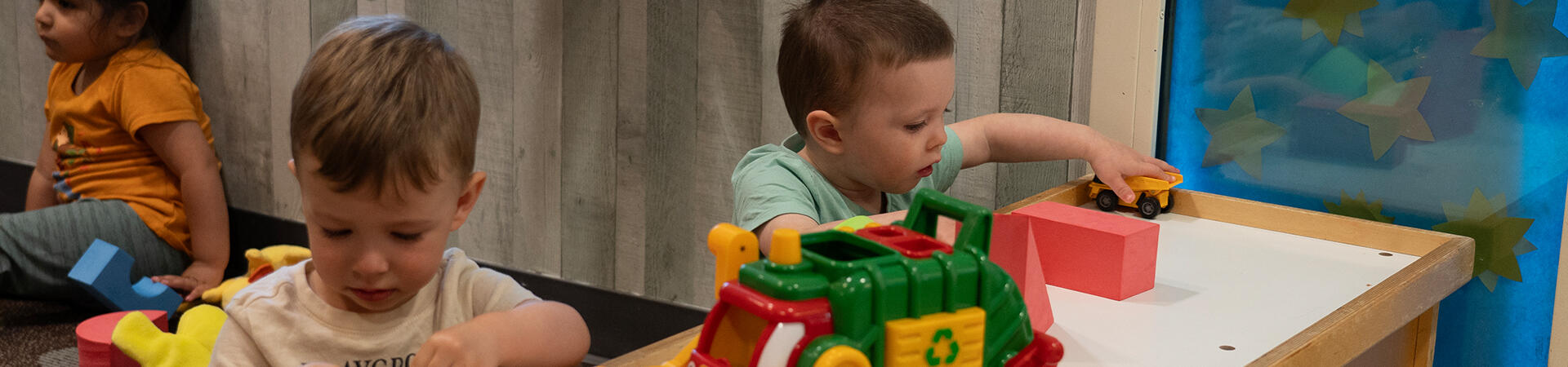 two toddlers playing with cars at table